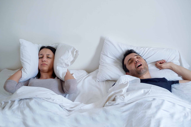 Man-snoring-woman-covering-her-ears