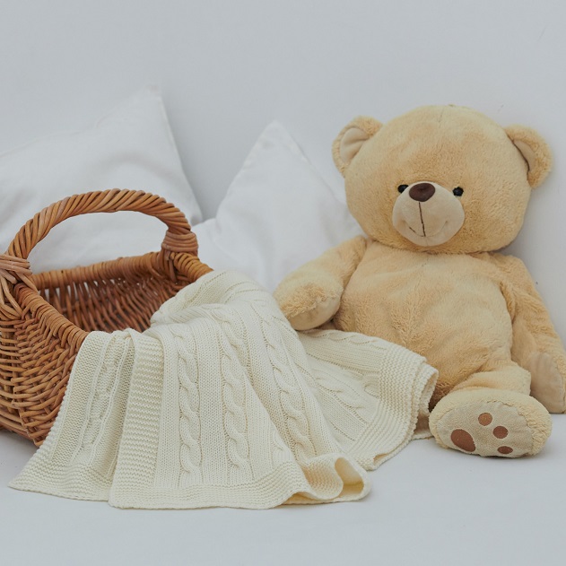 picture of a gift baby blanket in a basket beside a stuffed bear