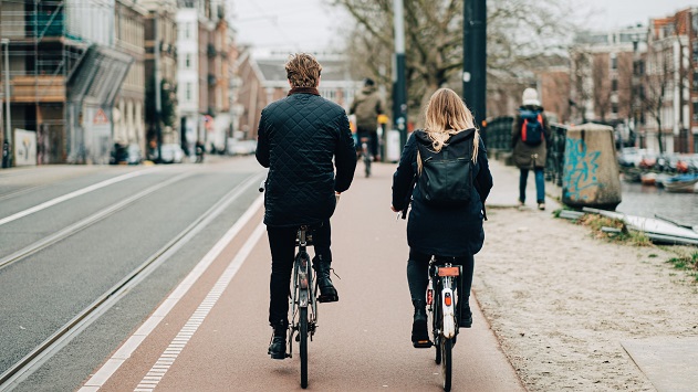 picture of a man and woman on bicycles driving across the city