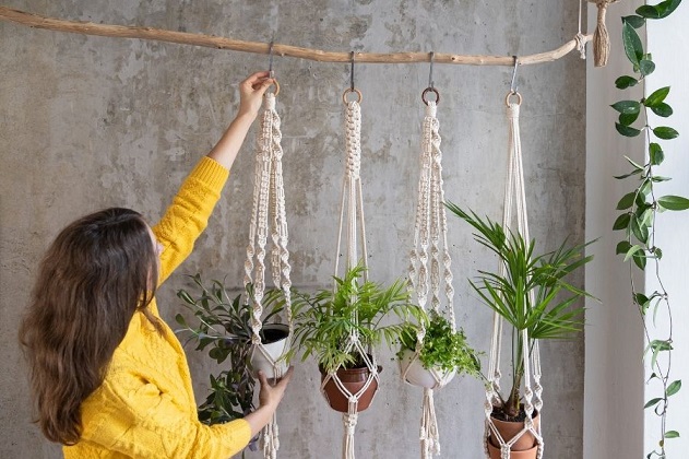 Woman decorating a room with hanging macrame pot hangers