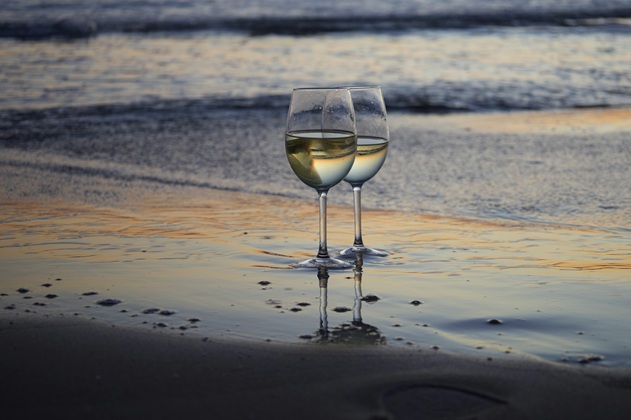 two glasses of white wine on the beach